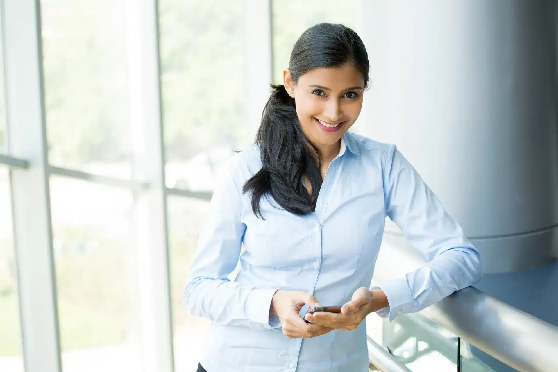 Young Woman Smiling While Holding her Cellphone