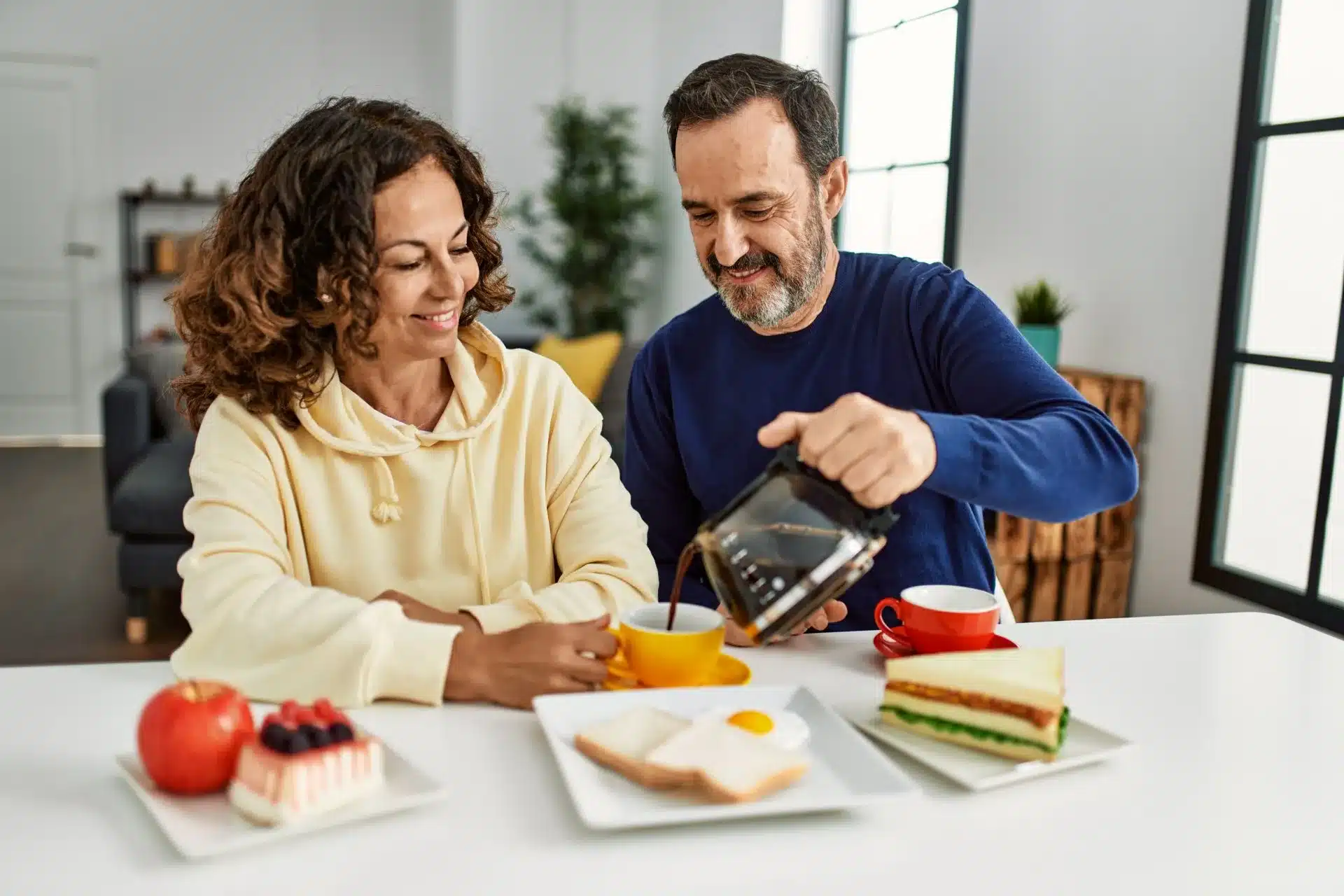 Middle Age Hispanic Couple Smiling while having their Breakfast